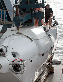 Carl Wood, the ship's Steward, plans tasty meals day in and day out. But he's also an expert swimmer. Here he stands atop Alvin while preparing for launch. Once the A-frame lowers the sub into the water, two swimmers play a pivotal role in releasing Alvin from the line that lowers it and getting the sub ready to dive.
