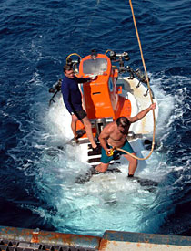 Swimmers Jerry Graham and Alvin technician Mark Spear help attach the sub to the line from the A-frame in order to bring it on board. 