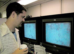 Geochemist Matt Jackson watches videotape of a recent Alvin dive. The same footage is on both screens because it is being duplicated. All Alvin video footage is duplicated for safekeeping. Scientists watch it to make "highlight" tapes of significant sections, and make notes that will help with future dives.