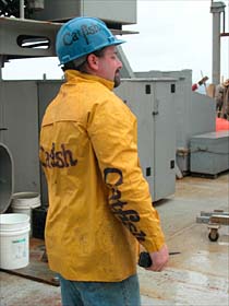 A man and his gear. Able Seaman Catfish with his personalized raingear and safety helmet, as he prepared early Saturday for an Alvin dive. Wind and rain blew across the ship this morning, but by the time Alvin had surfaced in the afternoon, a bright sun shone through breaking clouds. 