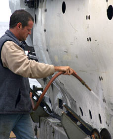 Salt water can corrode Alvin&rsquo;s thrusters and other aluminum parts, and it is tough on electrical equipment like cameras, so after each dive the sub receives a freshwater rinse. Gavin Eppard, a mechanical technician with the Alvin group, takes a turn with the hose.