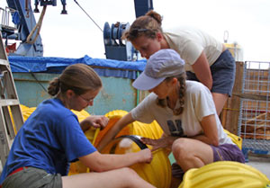Biologists Stace Beaulieu (in hat), Abby Knee (blue shirt), and Breaa Govenar spend the afternoon checking 17 glass ball floats for cracks and chips. The glass balls, protected by yellow plastic cases, provide flotation for moorings that will be deployed once we reach our research site.
