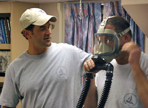 Chief pilot Bruce Strickrott (left) and pilot in training Mark Spear demonstrate the use of an emergency breathing apparatus (EBA). There are three EBAs in Alvin, one for each person.