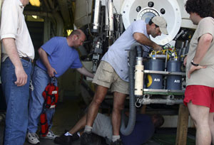 Alvin chief pilot Bruce Strickrott (in hat) and pilot in training Anthony Berry (under the basket) check that science equipment and instruments are properly attached to the sub before its dive.
