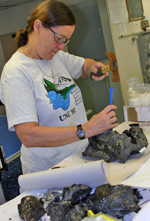 Geochemist Susan Humphris chips fresh, glassy lava from seafloor rocks collected using Alvin. The chips will be analyzed on shore to determine their chemical composition. (Photo by Amy Nevala)