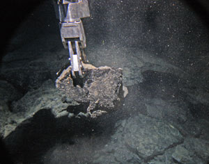 Alvin&rsquo;s manipulator arm samples a rock from the axis of the Galapagos Rift. (Photo by Adam Soule)