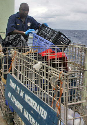 Oiler Charlie Apudo separates accumulated plastic waste, including these broken laundry baskets, which will be incinerated on the ship. �We are required by law to separate it,� he said. �And it makes sense for the environment.� (Photo by Amy Nevala)