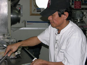 Romeo Agonias, at the deep fryer, prepares a treatchicken Kiev for lunch.