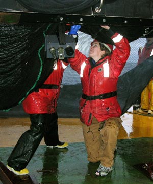 Wally Fulweiler, graduate student at the University of Rhode Island Graduate School of Oceanography, crawls under the MOCNESS to fasten it securely after the tow. (Photo by Isabelle Williams, ENSR Corp.)