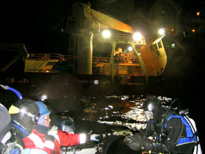 the L. M. Gould recedes behind the dive boat. Peter, one hand on the tiller and one for the radio, communicates with the ship as Kerri Scolardi (right) checks her depth-recording dive computer.