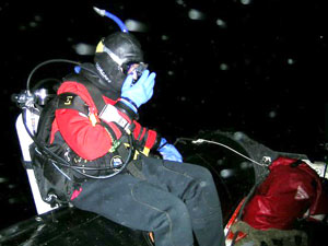 Kelly Rakow holds her mask as she prepares to flip backwards into the black water. Divers do this so the mask doesn’t come off unexpectedly when they go in.