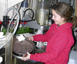 Marine Technician Jamee Johnson positions the MOCNESS frame in its cradle as the winch lowers it.