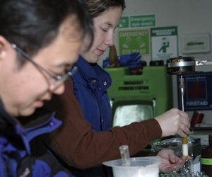 Twenty minutes after the bongo net returns, Wally (background) grinds salp guts to extract the plant pigments (colored compounds). Jun Nishikawa measures individual salps. (Photo by Larry Madin, WHOI)