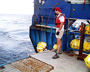 Bruce Strickrott waits to deploy another transponder on the fantail of Atlantis. The yellow transponder is hanging from a line that is used to gently lower it into the water. When Bruce gets the word from the Bridge and Top Lab that they are in the right position, he deploys the transponder.