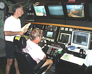 The row of TV monitors permit the fish flyer (Yogi) and the watch leader (Mike) to see that the cable is smoothly winding on and off the winch spool, and passing through the block on the A-frame on Melville’s stern (leftmost monitor). Any snarling of the cable along its path could cause it to jam, or snap with tremendous force! So it is very important for everyone’s safety that the watch standers keep an eye on the TV monitors at all times.