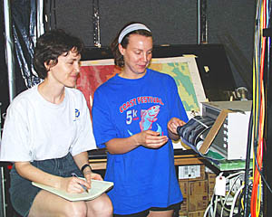 Watch leader Maya Tolstoy and Julia Getsiv look at the first four hours of the DSL-120 sidescan sonar records as they are coming off the plotter. Directly behind Julia is the multibeam bathymetry map on which Julia plots the positions of the ship and the DSL-120 sonar “fish” every ten minutes. P.J. Bernard, who is “flying” the vehicle over the seafloor then knows whether hills or valleys will be coming up. 