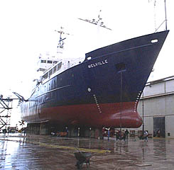 The R/V Melville when she was in drydock in San Diego in January 2000. R/V Melville goes into drydock about every two and a half years to have her hull cleaned and painted, and for overhaul of the various mechanical systems onboard. Maintaining a clean hull is important. A hull fouled with marine growth increases fuel consumption and reduces the speed.