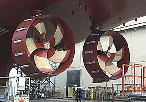 A close-up of R/V Melville’s stern thrusters. The ship does not have rudders. R/V Melville steers by rotating the thrusters on a vertical shaft to get thrust in any direction. The propellers are nine feet in diameter. The nozzles help direct the stream of water from the propellers, and they also help eliminate side forces caused by them. The light colored bars on the nozzles are sacrificial zinc anodes that help protect the hull and immersed steel work from electrolysis. If there are electric currents, the zinc will dissolve before the current starts attacking the metal of the ship.