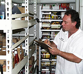 Dan keeps track of all the canned goods and dry stores -- a big job in itself! The racks behind Dan are for 1 gallon-sized containers of everything from tomatoes, vegetables, fruits and other staples and condiments.
