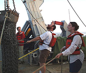 Randy Dickau, one of the Scripps Resident Technicians, directs the dredging operations off Fernandina Island as Peter Lean (background) and Julia Getsiv tend the safety lines. 