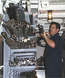 Dennis Barclay selects the right piece of tubing for the repair job he is working on. Having a good supply of many different types of materials in different sizes is important to being able to make repairs at sea. You cannot run down to the local hardware store if you do not have the right material!