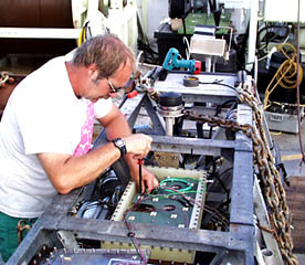 While others look at rocks, Bob “Yogi” Elder connects the fiber optic cable to Argo II in preparation for today’s lowering.