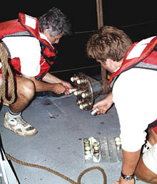 Dan Fornari (left) and Ben Wigham insert the cutters into the head of “Mighty Mo”, the wax corer. The yellow stuff on the tips of the cutters is surfboard wax. When “Mighty Mo” hits the lava surface, chips of the glassy rind get stuck in the wax.