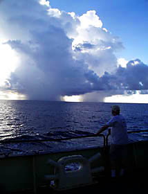 The Knorr passes five miles east of afternoon cumulonimbus clouds. The giant, mushroom-shaped clouds produce showers when warm air from the ocean surface rise, condense, and fall as rain. The upper white part consist of ice crystals; the lower dark part is rain. “It’s great to look at. I’m just glad we didn’t have to go through it,” said cloud enthusiast and chemical oceanographer Bob Collier.