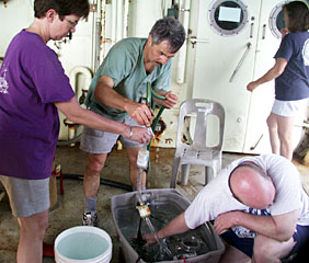 Scientists test a slurp sampler, which literally slurps up shrimp, snails and other small organisms from the hydrothermal vent sites. “It’s like a vacuum cleaner underwater,” said biologist Tim Shank, ducking his head to avoid a soaking from fellow scientists Colleen Cavanaugh and Dan Fornari. (He stayed dry).