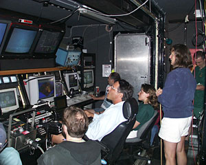 Inside the watch van, all eyes are on the video monitors displaying the black smoker chimneys. Marine Geochemist Susan Humphris (in blue) is too excited about the discovery to sit. 