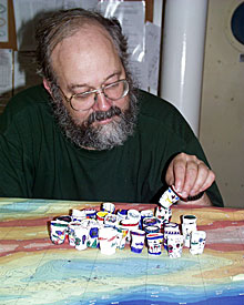 Oceanographer Bob Collier examines squished Styrofoam cups returned from the high-pressure ocean depths. His daughter’s third grade class decorated the cups then sent them with Bob for a “shrinking” in the Indian Ocean.