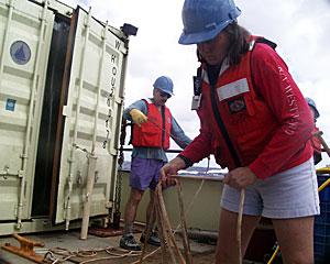 Geologists Dan Fornari and Susan Humphris coil the lines used to steady the dredge when it is lifted over the side and lowered into the water.  