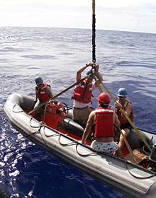The crane lowers the workboat with crew members Kent Sheasley, Adam Seamans, Bill Dunn and DSOG team member Fran Taylor to recover the new elevator. It returned to the surface this morning with a full load of samples after its first seafloor visit.