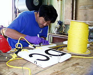 Graduate student Yong-Jin Won makes lettered markers to place at each sampled hydrothermal vent. The white rectangle markers are made of a special material called syntactic foam. A three-foot yellow line attaches the marker to an anchor.