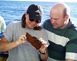Biologists Shana Goffredi and Tim Shank examine tiny tubeworms living on a rock brought from the Edmond vent field today on the elevator.  