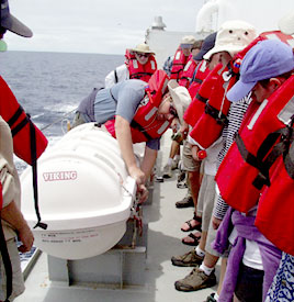 The whole ship's company participated in fire and boat drills after lunch to insure that everyone knows what to do in an emergency. Here Eric Wakeman, the first mate, demonstrates how to deploy a life raft while the scientists look on.