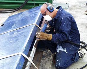 Victor Barnhart, the Bosun, chips paint from a railing. This is to remove all rust and old paint so it can be re-painted anew. Daily maintenance of the ship is important to keep everything running smoothly.