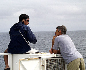 Sitting on the bow, Francisco Cruz, an observer from the Charles Darwin Research Station, chats with Dan Fornari about his work. Using binoculars, Francisco is taking a census of the number and types of sea birds as part of an ongoing project run by the Darwin Station.