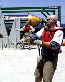  Bob Reynolds (background) and Steve Volpe keep a tight hold on the tag lines to keep the dredge from swinging as it is deployed. 