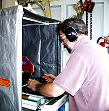  Alberto Saal cuts rocks into slabs using the rock saw in the hanger bay. He wears eye and ear protection while cutting.  