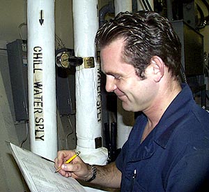  Sean Mix, Oiler, takes notes on his rounds in the engine room to make sure that everything is running smoothly. 
