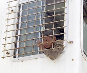  Eduardo Angeles, Oiler, watches the wire go out on the dredge winch from the trawl shack. The bars on the window protect him in case the wire breaks. 