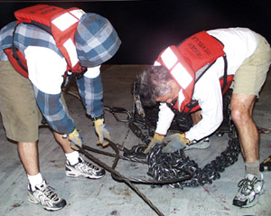  Steve Volpe (left) and Dan Fornari work to untie the knot in the dredge chain.  