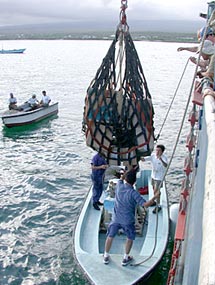 The crew of R/V Atlantis offloads computers to be used by the Darwin Research Station and local schools. Dell Computer donated five new computers through the World Wildlife Fund, and Woods Hole Oceanographic Institution also donated used computers. 