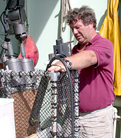 Expedition Leader Pat Hickey works on fitting the titanium water sampling bottles and the temperature probe into Alvin’s basket.