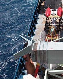 Ordinary Seaman Robert Hill gives a winch beam a fresh coat of paint. This winch had electrical problems earlier; with the first dive day approaching, all our equipment has to be fully ready to go. In the background sits ABE, an unmanned sub that makes fine-scale maps and photomosaics.