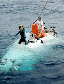 Able Seaman Patrick Hennessy dons his wetsuit just before Alvin was set to dive. Two swimmers always accompany the submarine before it goes underwater, and when it re-surfaces. They attach the lines that are used when Alvin is deployed and retrieved.