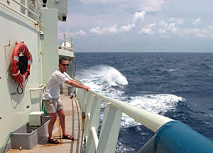 Science writer Joe Appel holds tight to the railing off the port side of R/V Atlantis. Winds were gusting at more than 30 knots, and swells were getting to 12 feet high. Under conditions such as these, deploying Alvin is not an option.