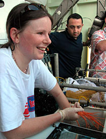 As Alvin pilot Anthony Tarantino looks on, biologist Rhian Waller holds fronds of a live soft coral called Iridio gorgia, or spiral gorgonian. It was in its spiral form when Alvin retrieved it from Muir Seamount, but it broke on the way up.