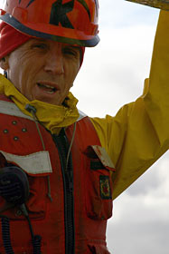 Mark Spear, a mechanical technician with the Alvin crew, prepares a transponder for dropping overboard. Transponders act as beacons to guide the submersible while exploring the seafloor. The hard yellow plastic case helps protect a glass ball, hydrophone, and computer panel inside.